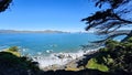The Golden Gate Bridge at Mile Rock Beach with blue ocean water, waves, rocks and lush green trees on Lands End Trail Royalty Free Stock Photo