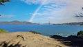 The Golden Gate Bridge at Mile Rock Beach with blue ocean water, waves, rocks and lush green trees on Lands End Trail Royalty Free Stock Photo