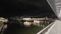 The Golden Gate Ferry Terminal with people walking at night and the San Francisco Oakland Bay Bridge with lights in San Francisco