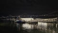 The Golden Gate Ferry Terminal with people walking at night and the San Francisco Oakland Bay Bridge with lights in San Francisco