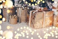 Golden gift box with bow on floor under Christmas tree surrounded with yellow bulb garland