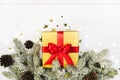 Golden gift box with red ribbon, christmas spruce border, confetti on white. Top view new year banner Royalty Free Stock Photo