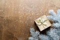 a golden gift box on a wooden table with gold spangles in the shape of stars, among the fir branches