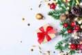 Golden gift or present box, snowy fir branches, conifer cones, Christmas decoration and red berry on white table top view