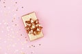 Golden gift or present box and stars confetti on pink background top view. Flat lay composition for birthday, christmas or wedding Royalty Free Stock Photo
