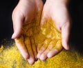 Golden glitter sand in hands on black, abstract background. Royalty Free Stock Photo