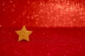 Golden glittering star on red glitter background. Festive abstract red glitter texture background with single golden star. Royalty Free Stock Photo