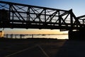 Golden glow of Morning sunrise on horizon under in silhouette railway bridge