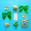 Golden and green Christmas gift boxes and decorations on blue background. Flat lay. Top view