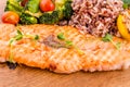 Golden grilled fish fillet with a side dish of rice and vegetables on a wooden board on a white background Royalty Free Stock Photo