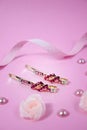 Golden hairpins with pink gemstone and pink polka dot ribbon on pink background