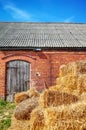 Golden haystack in front of an old brick barn building