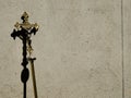 Golden holy processional cross leaning on a concrete Wall with shadow