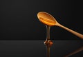 Golden honey dripping from a spoon on a reflective surface minimalist black background Royalty Free Stock Photo