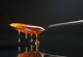 Golden honey dripping from a spoon on a reflective surface minimalist black background Royalty Free Stock Photo