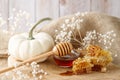 Golden honeycombs with fresh natural honey and glass bowl with dipper with decor white pumpkin and flowers. Fresh harvesting