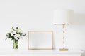 Golden horizontal frame and bouquet of fresh flowers on white furniture, luxury home decor and design for mockup Royalty Free Stock Photo