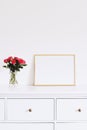 Golden horizontal frame and bouquet of rose flowers on white furniture, luxury home decor and design for mockup creation Royalty Free Stock Photo