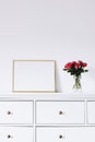 Golden horizontal frame and bouquet of rose flowers on white furniture, luxury home decor and design for mockup creation Royalty Free Stock Photo