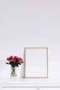 Golden horizontal frame and bouquet of rose flowers on white furniture, luxury home decor and design for mockup creation Royalty Free Stock Photo