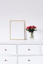 Golden horizontal frame and bouquet of rose flowers on white furniture, luxury home decor and design for mockup creation Royalty Free Stock Photo