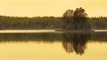 Golden hour beautiful reflection of small island in lake. Royalty Free Stock Photo