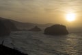 Golden Hour Brilliance: A Sunset Over the Ocean with Rocky Cliffs Standing Guard Royalty Free Stock Photo