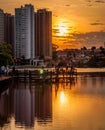 Golden hour with buildings reflected on water of a lake in a park. Some people on the parks deck enjoying the view. Royalty Free Stock Photo