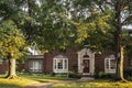 Golden Hour on the maple trees in front of traditional brick house with columns and bay windows - light stretching across front ya