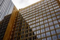 Golden-hued building adorned with reflective glass windows against a sleek, dark-toned structure Royalty Free Stock Photo