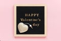 Golden inscription Happy Valentines day and decoration textile heart on black letter board, central composition on pink