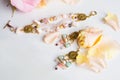 Golden jewerly braslete and earning with semiprecious and roses petals at white background