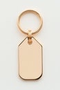 Golden keychain featuring blank metallic tag, hanging on white surface, ready for personalized engraving Royalty Free Stock Photo