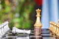 A golden king chess piece standing on a stack of dollar coins and a silver king chess piece failing to beg for mercy on a chess bo Royalty Free Stock Photo