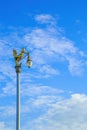 Golden Kinnaree on light pole against blue sky