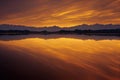 Golden lake and mountains under sunrise dramatic sky.