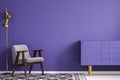 Golden lamp near a gray armchair and ultra violet cupboard in si