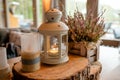 White lantern with burning candle inside it standing on festive table decorated on wooden slice and flowers on Royalty Free Stock Photo