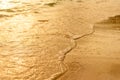 Golden light reflecting off a water wave at the sea and sand on sunset. Pure Gold Royalty Free Stock Photo