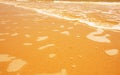 Golden light reflecting off a water wave at the sea and sand on sunset. Pure Gold Tone Royalty Free Stock Photo