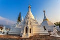 Golden light shining on white and gold pagoda during sunrise / sunset with blue sky