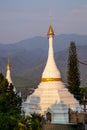 Golden light shining on white and gold pagoda during sunrise / sunset with blue sky