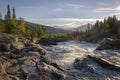 Golden light shining on wild river flowing down the beautiful Swedish landscape