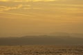Golden light of sunrise behind the mountains in the sea and shadow fishing boats
