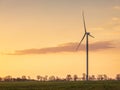 Golden light of sunset in the sky and view to silhouette of wind generator