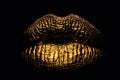 Golden lips closeup on balck. Gold metal lip. Beautiful makeup. Golden lip gloss on beauty female mouth, closeup. Mouth