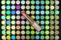 Golden lipstick on colorful eyeshadow palette background. Flat lay