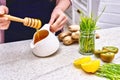 Golden liquid Organic Honey on a drip pouring Green wheat, lemon and ginger for a detox smoothie Royalty Free Stock Photo