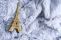 Golden little statuette of the Eiffel Tower on gray fur plaid