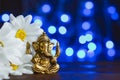Golden lord Ganesha sculpture in daisy flowers over blue illuminated background. Copy space for text Royalty Free Stock Photo